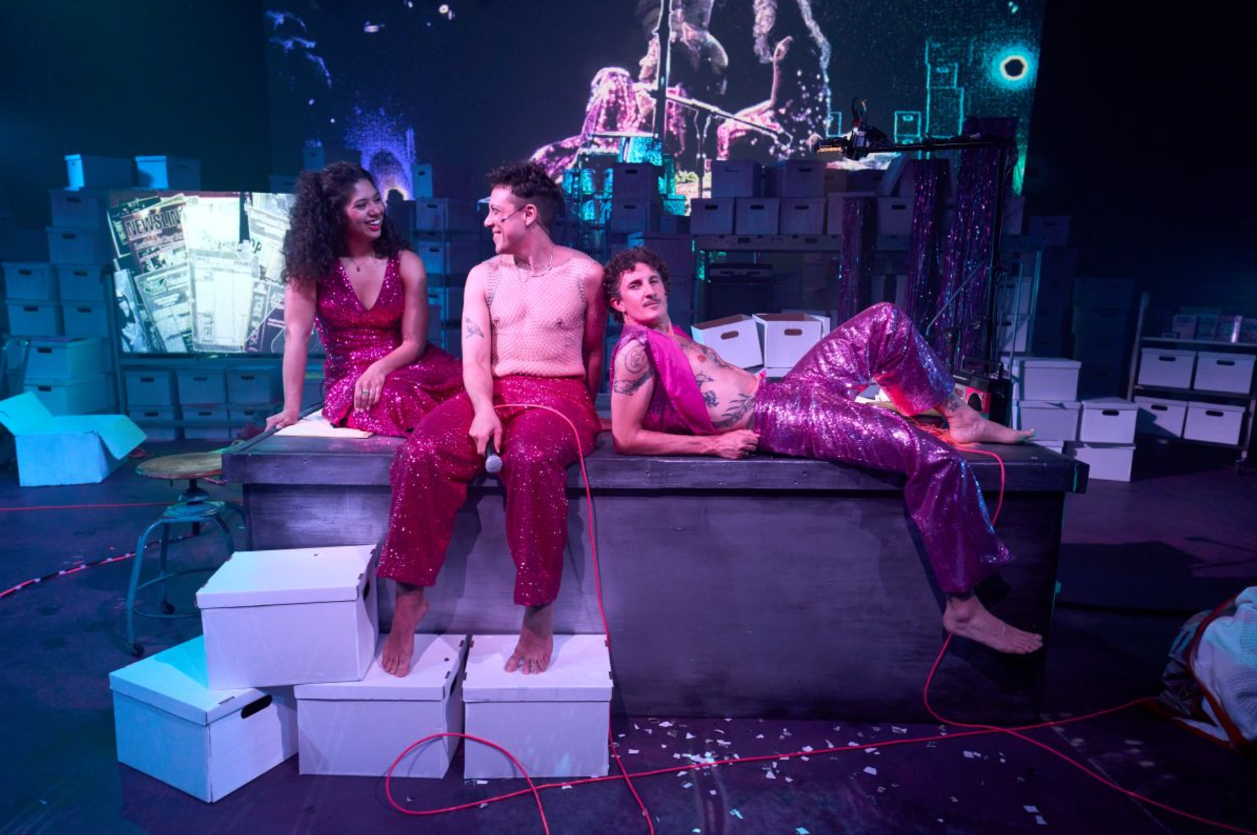 Three performers in vibrant costumes on a stage.